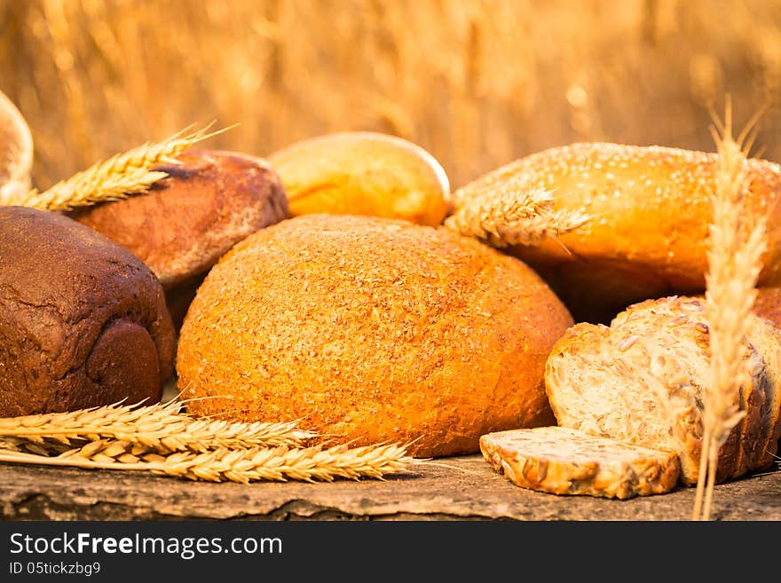 Homemade bread and wheat on the wooden table in autumn field