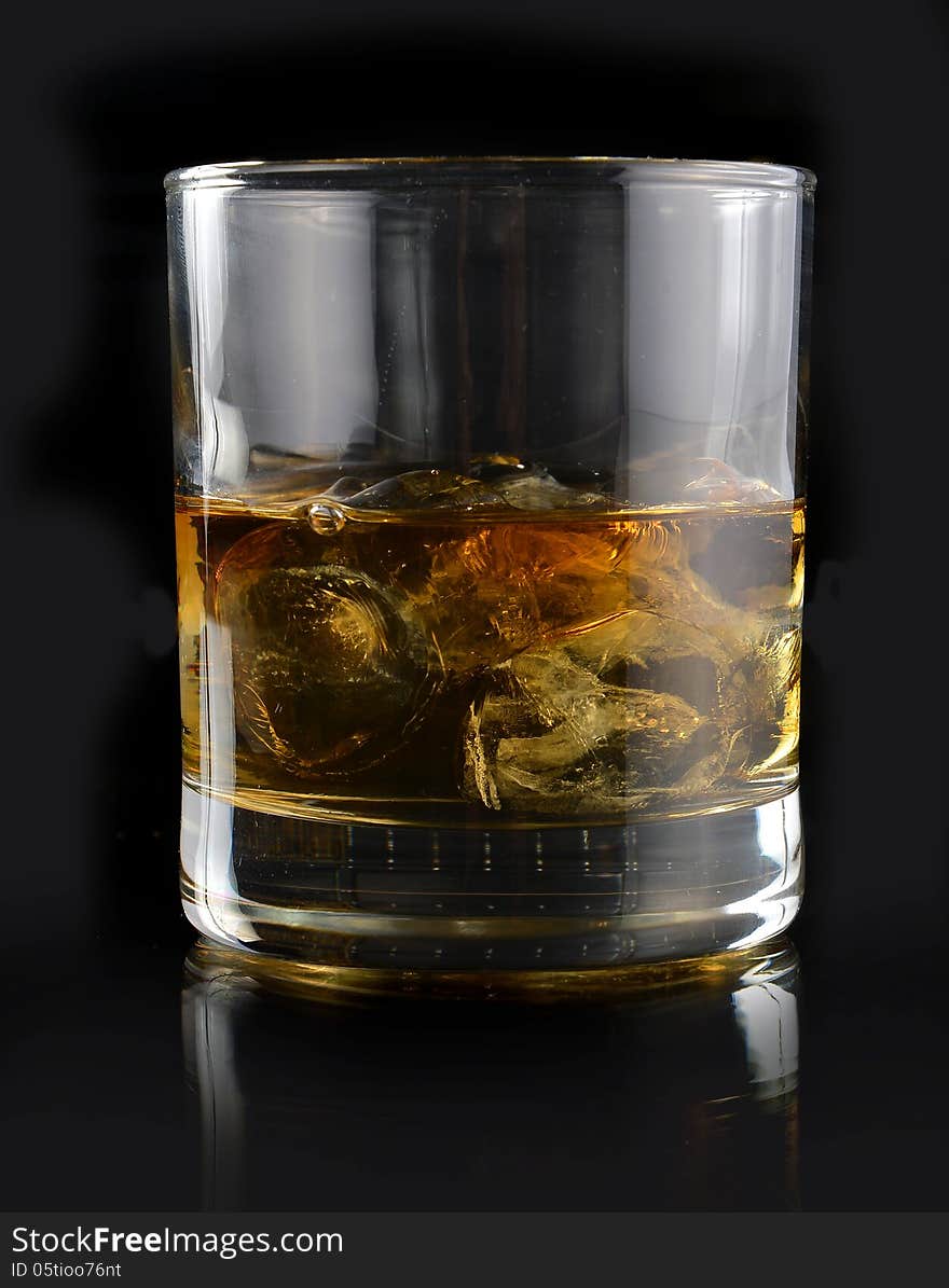 Whiskey with ice in a glass on a black background