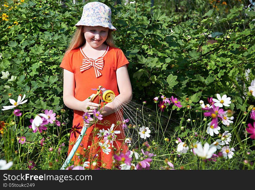 Little girl watering flowers in garden