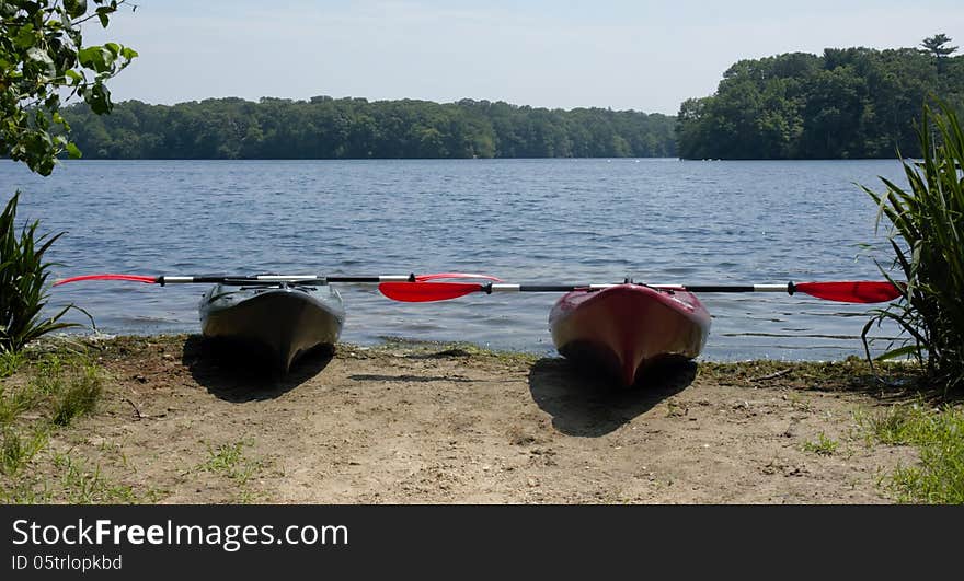 Couple of kayaks with paddles on the lake ready for ride ,nature is quit and beautiful. Couple of kayaks with paddles on the lake ready for ride ,nature is quit and beautiful