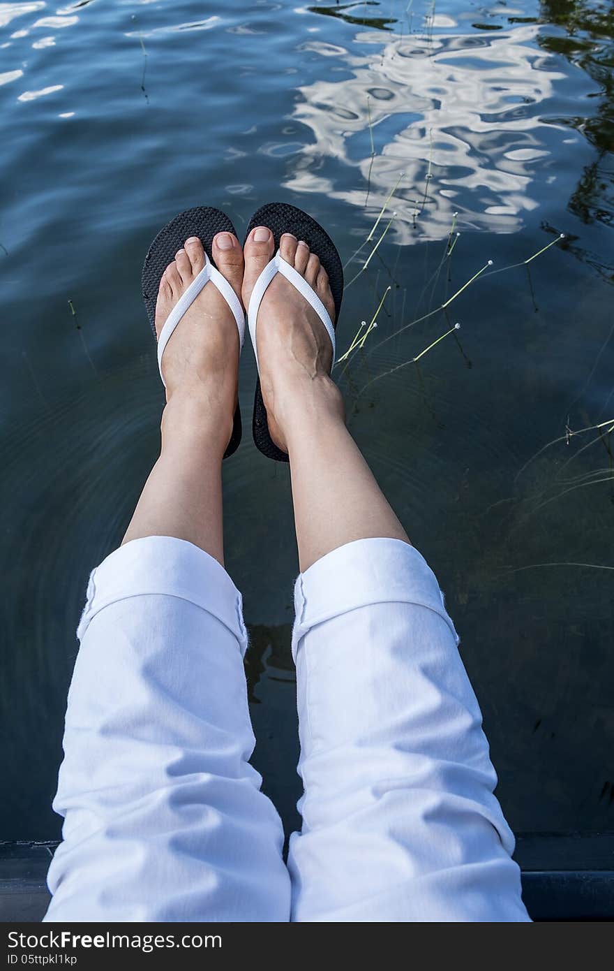 Feet Wearing Flip Flop Hanging Over a Lake