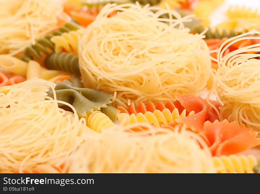 Different pasta in three colors close-up on the white background. Different pasta in three colors close-up on the white background.