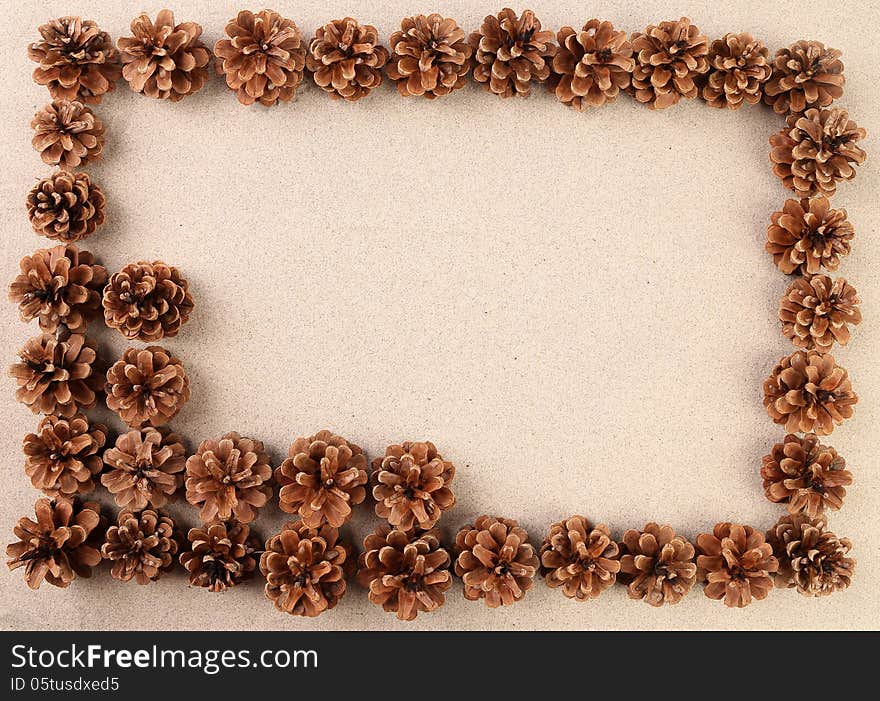 Pine cones arranged on the sand. Frame.