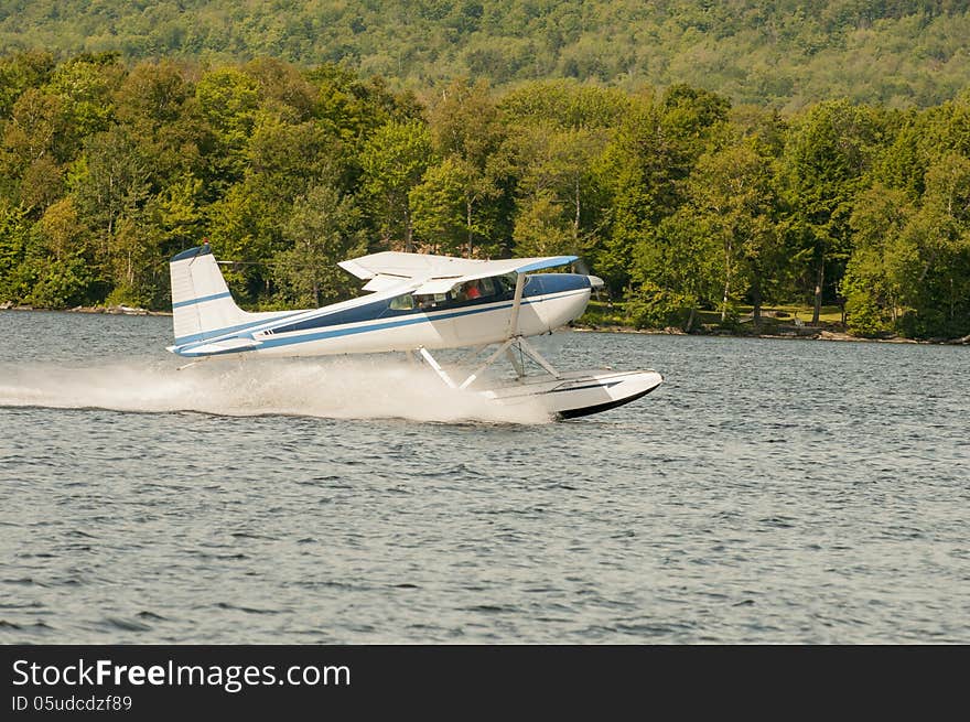 Flying float plane or seaplane taking off at a lake.