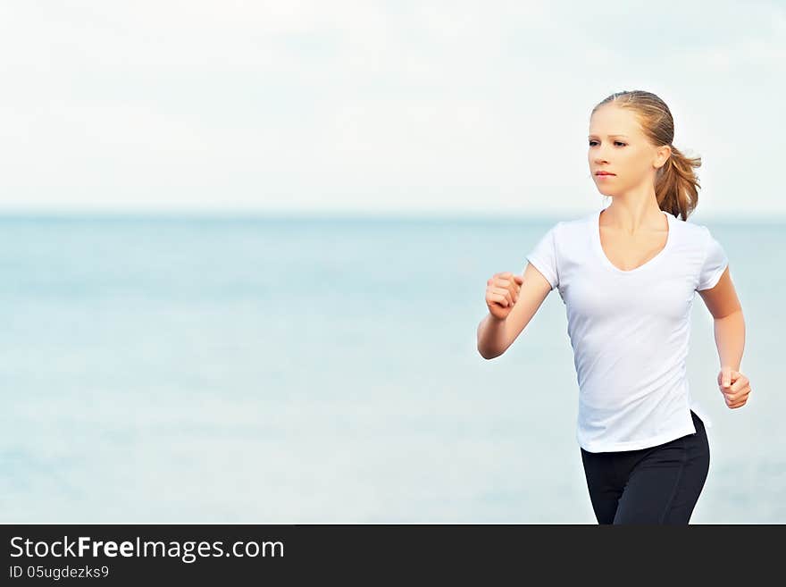 Young woman running on the beach on the coast of the Sea