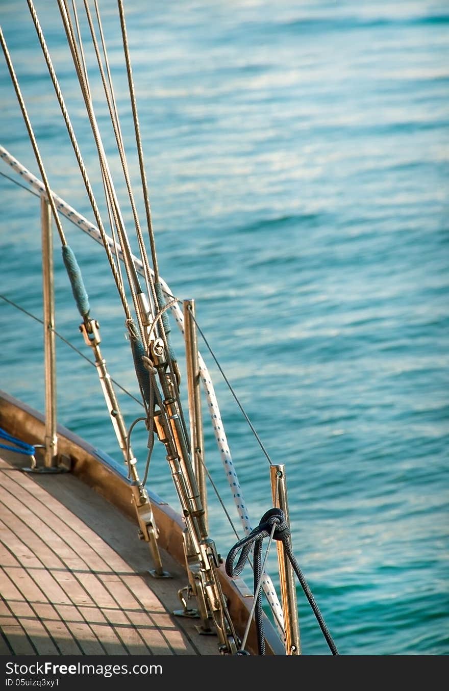 Sailing boat on sea background. Marine ropes and tackles for the rigging yacht. Wooden deck on the yacht with sea ropes.