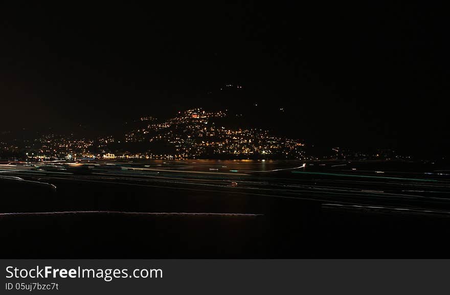 Long exposure on Lugano Lake, the lights of boats navigating the lake leave a luminous trial on the dark surface of the lake. Long exposure on Lugano Lake, the lights of boats navigating the lake leave a luminous trial on the dark surface of the lake