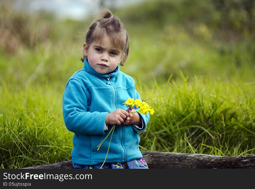 Little girl holds yellow flowers