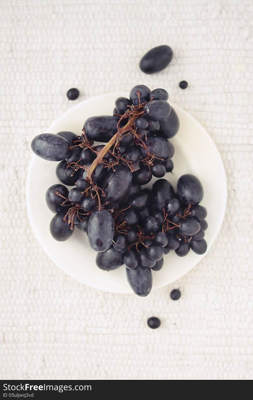 Black grapes on a white plate top view