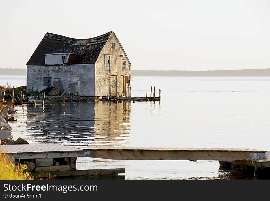 A derelict fishing hut and boat house on the ocean in need of TLC or a wrecking ball. A derelict fishing hut and boat house on the ocean in need of TLC or a wrecking ball.