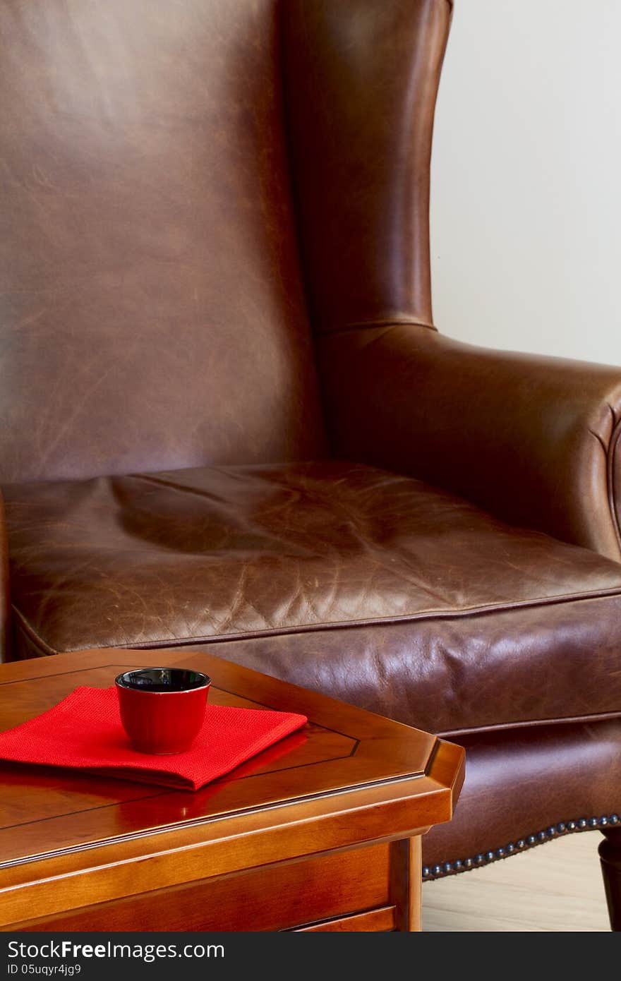 Coffee table a cup for coffee on a napkin and a leather armchair. Coffee table a cup for coffee on a napkin and a leather armchair