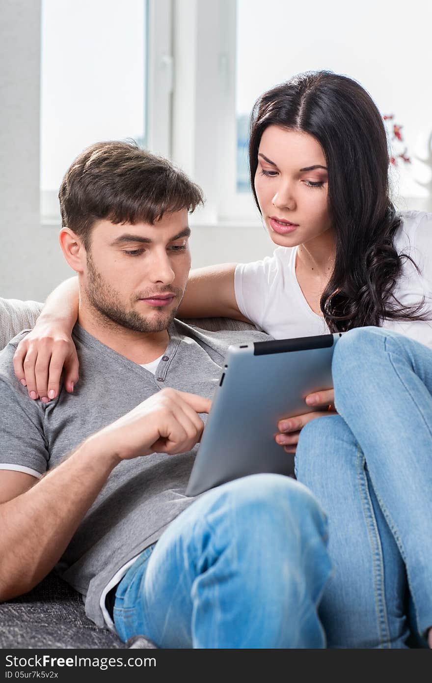 Young couple sitting on the couch with tablet computer. Young couple sitting on the couch with tablet computer