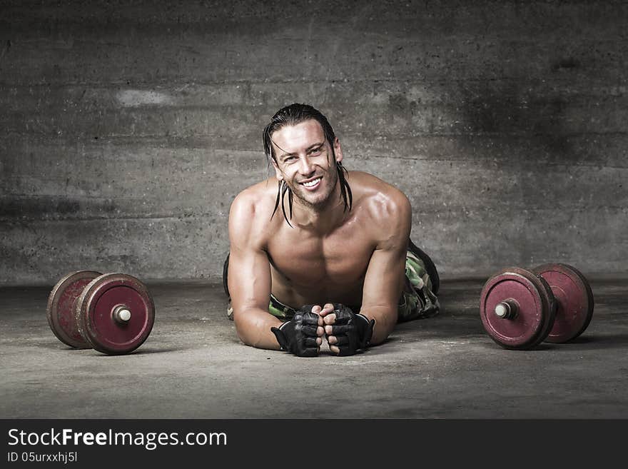 Portrait of muscle and smiling athlete lying on the floor