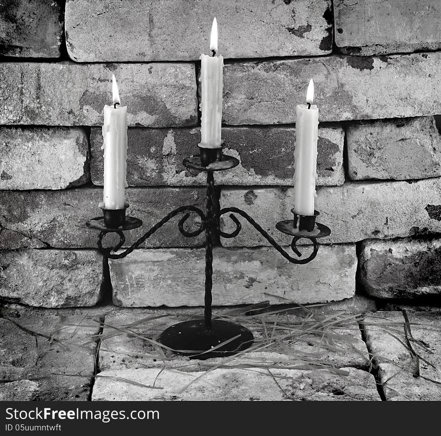 Black and white image of three burning candles on stone wall background. Black and white image of three burning candles on stone wall background