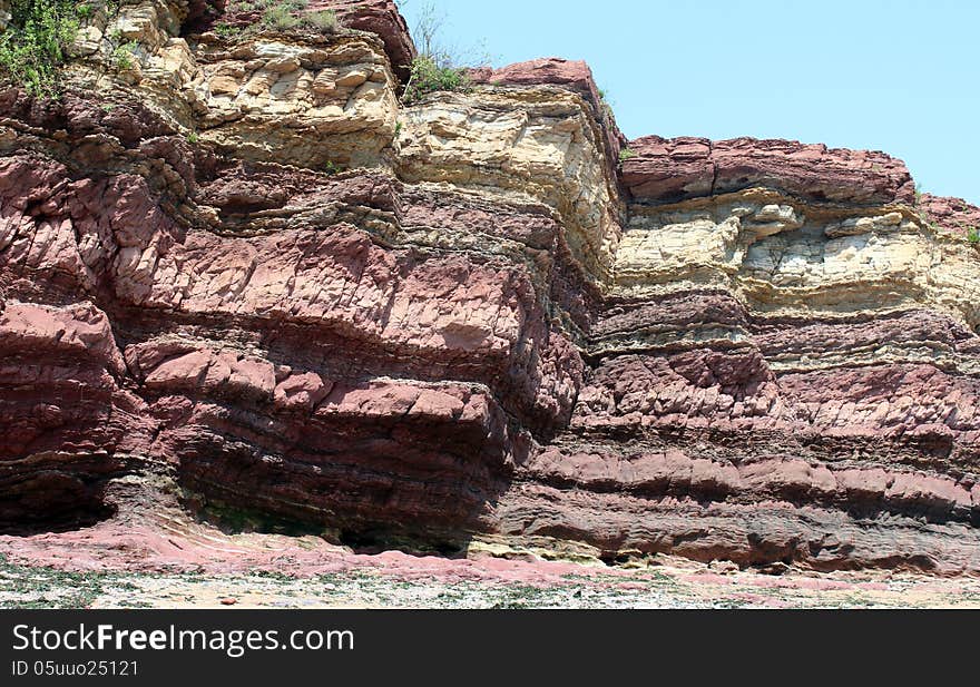 A huge laminated rock under the sunshine shows red and yellow color. A huge laminated rock under the sunshine shows red and yellow color.