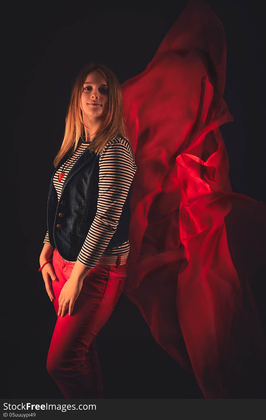 Beautiful girl against red fabric in the dark