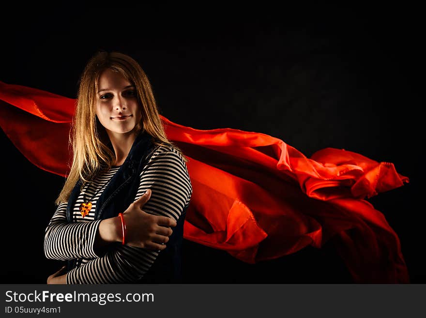 Beautiful girl against red fabric in the dark with long blond hair