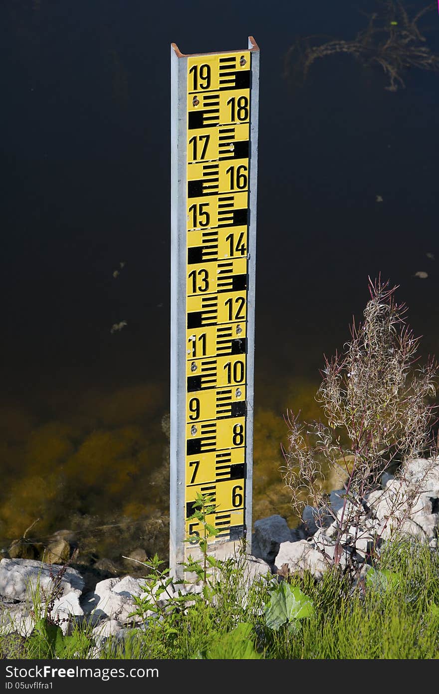 A yellow water level detector on the edge of a lake