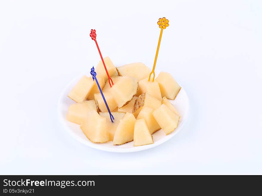 Fresh melon cubes on a plate. White background.