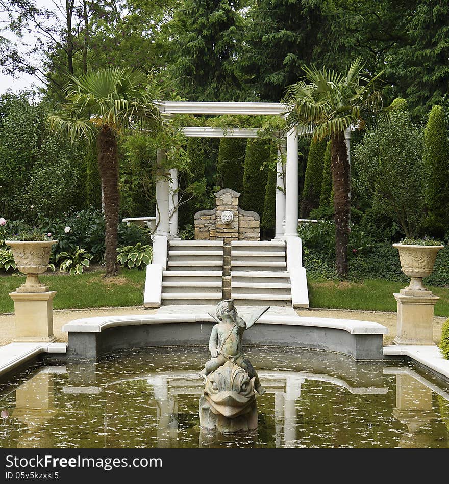 Pont with statues and palm trees in a formal Italian garden