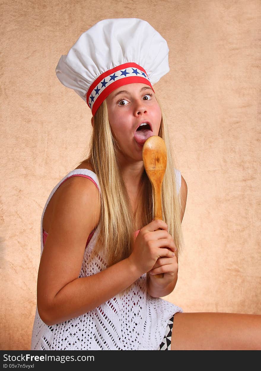 Teenage Female With Bakers Hat Licking Cooking Utensil Spoon. Teenage Female With Bakers Hat Licking Cooking Utensil Spoon