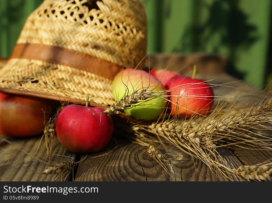 Rural abstract summer still life with apples, ears of wheat and straw hat. Rural abstract summer still life with apples, ears of wheat and straw hat.