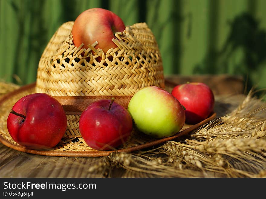 Rural abstract summer still life with apples, ears of wheat and straw hat. Rural abstract summer still life with apples, ears of wheat and straw hat.