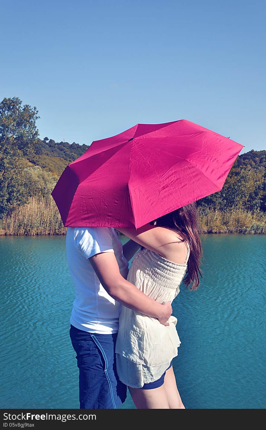 A rocker couple kissing under an umbrella.