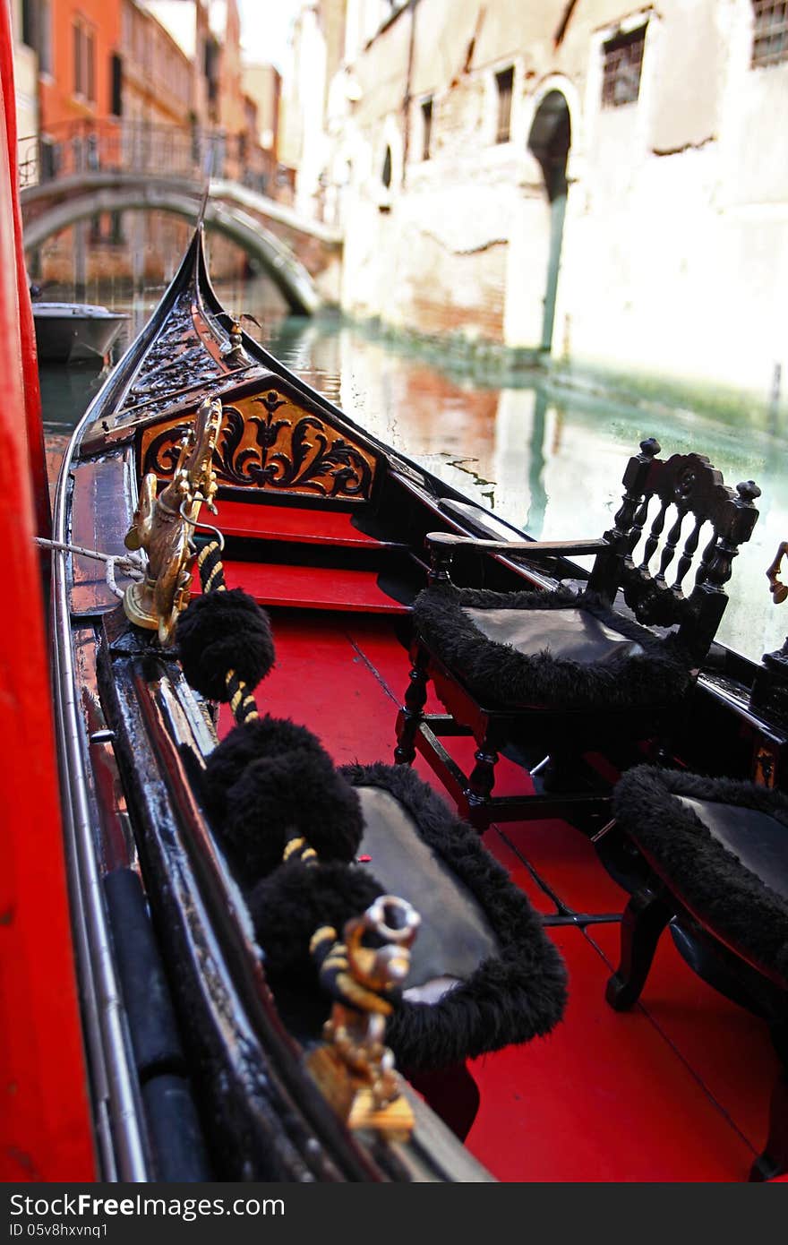 Venetian gondola closeup view with blurred bridge across canal on background