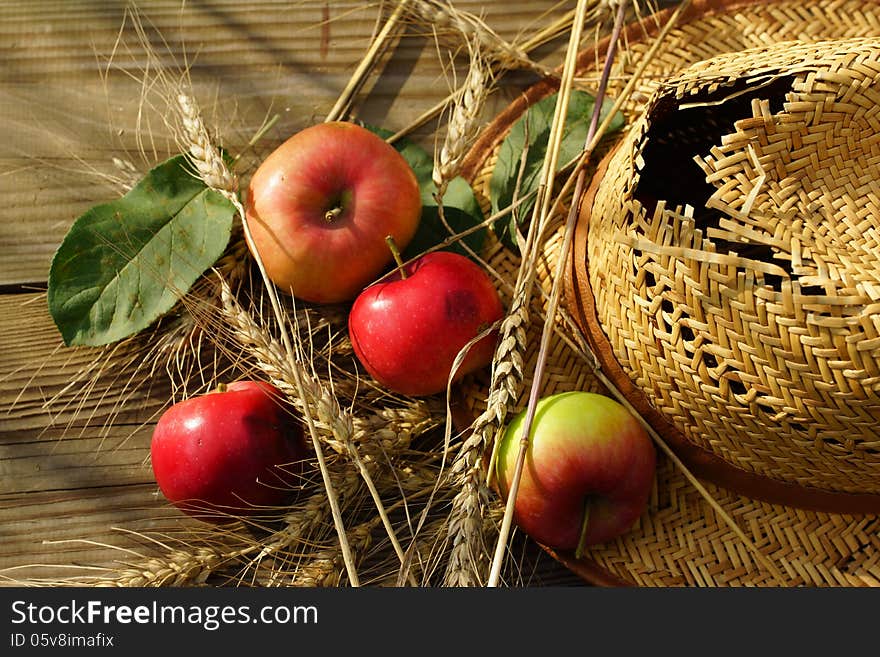 Composition with apples, stalks and straw hat.