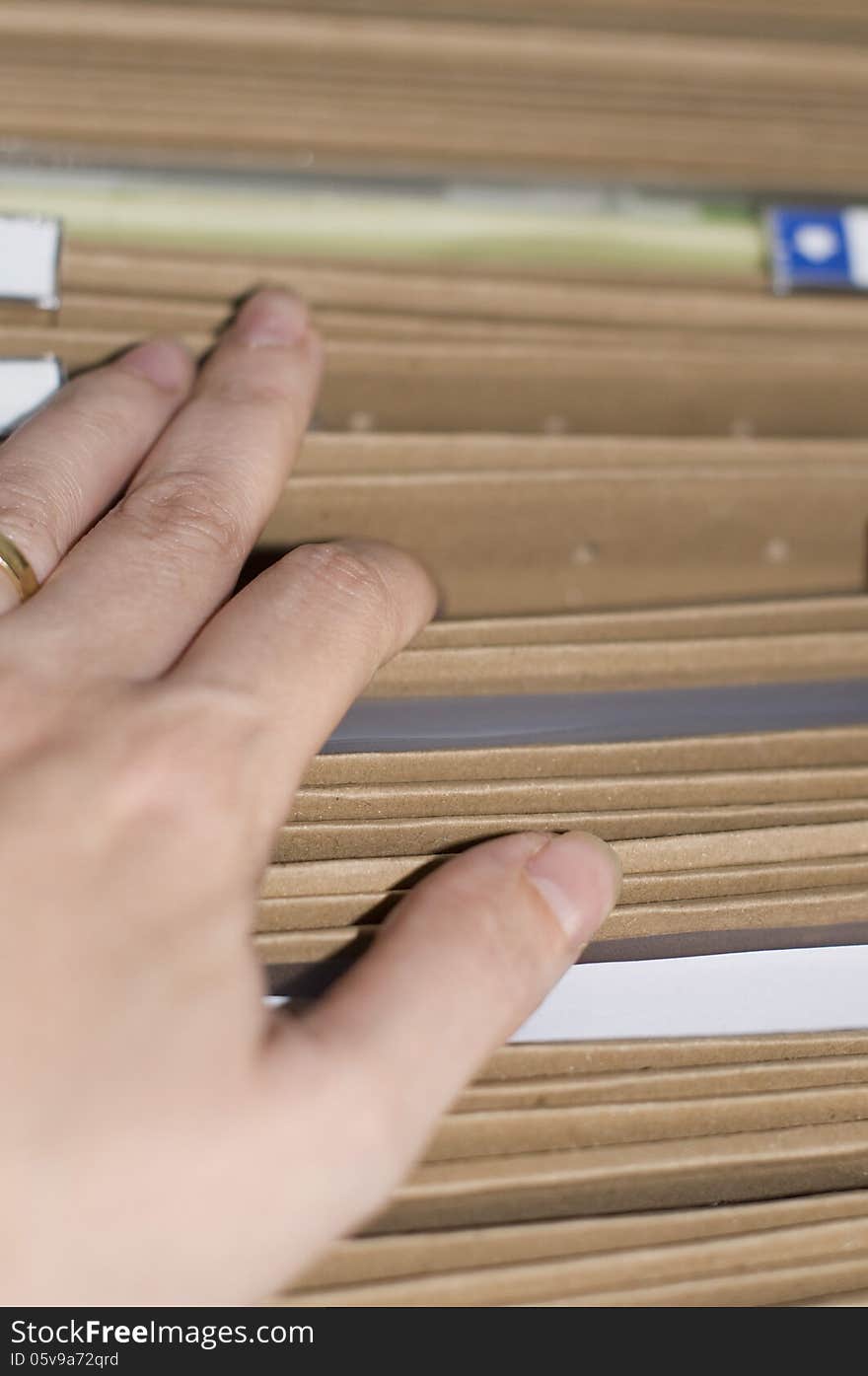 A hand of someone searching a document in a file cabinet. A hand of someone searching a document in a file cabinet