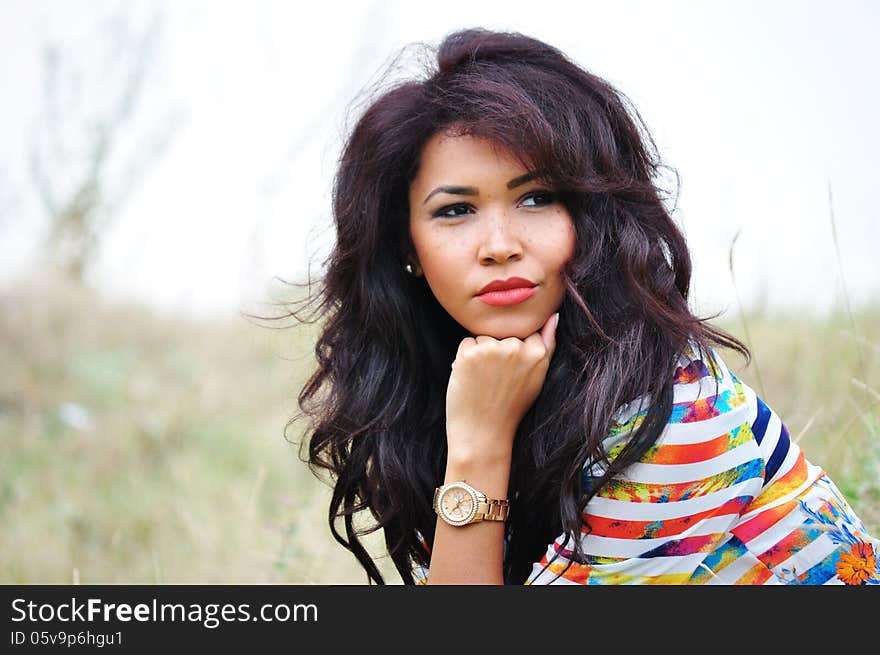 Outdoor portrait of an attractive young woman with long blac hair.