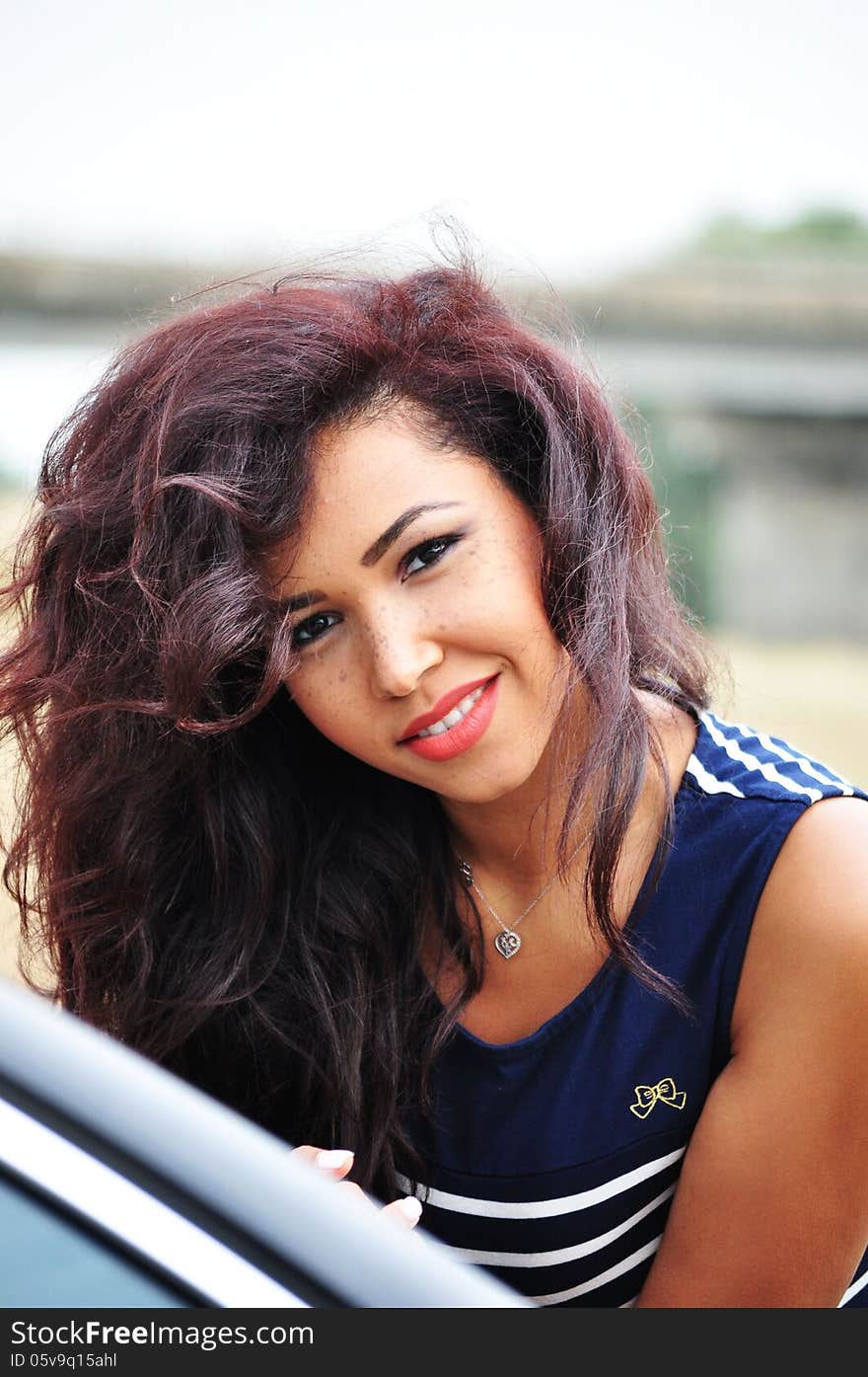 Outdoor portrait of an attractive young woman with long blac hair.