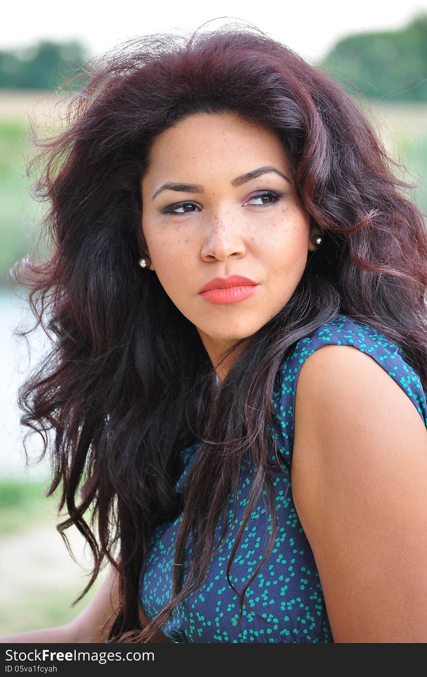 Outdoor portrait of an attractive young woman with long blac hair.