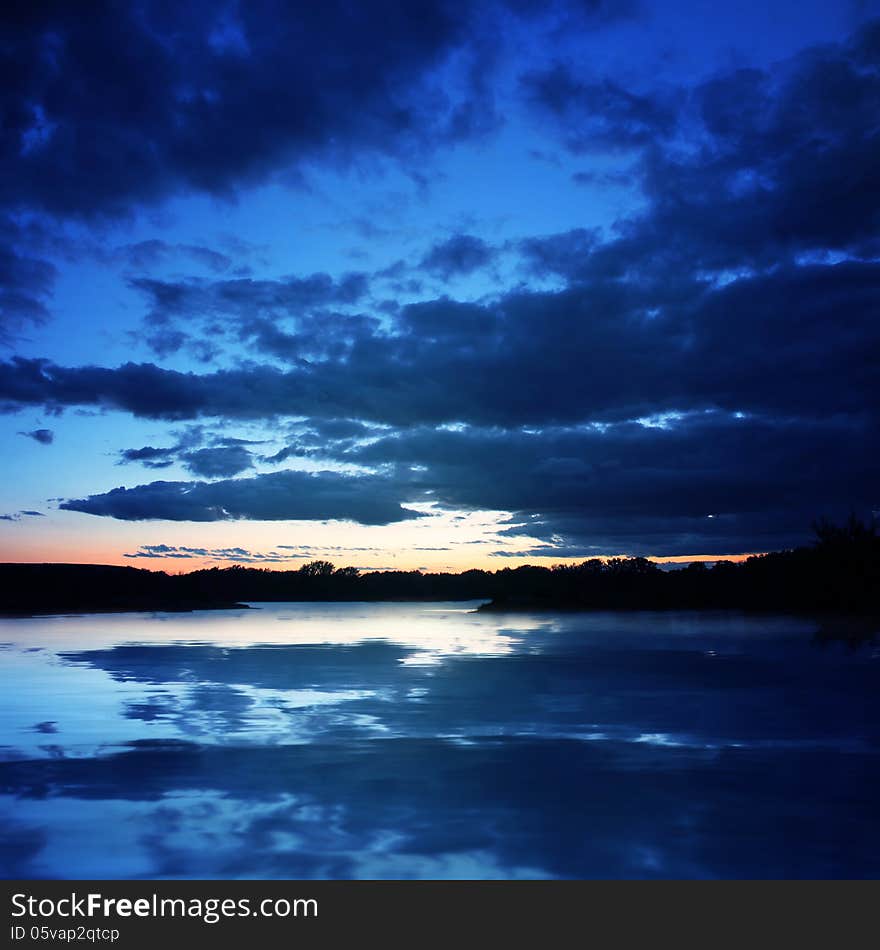 Background of dark sky before a thunder-storm with reflection in the water