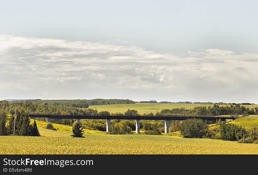 A railway bridge over a gully surrounded by farmland and dotted with trees. A railway bridge over a gully surrounded by farmland and dotted with trees