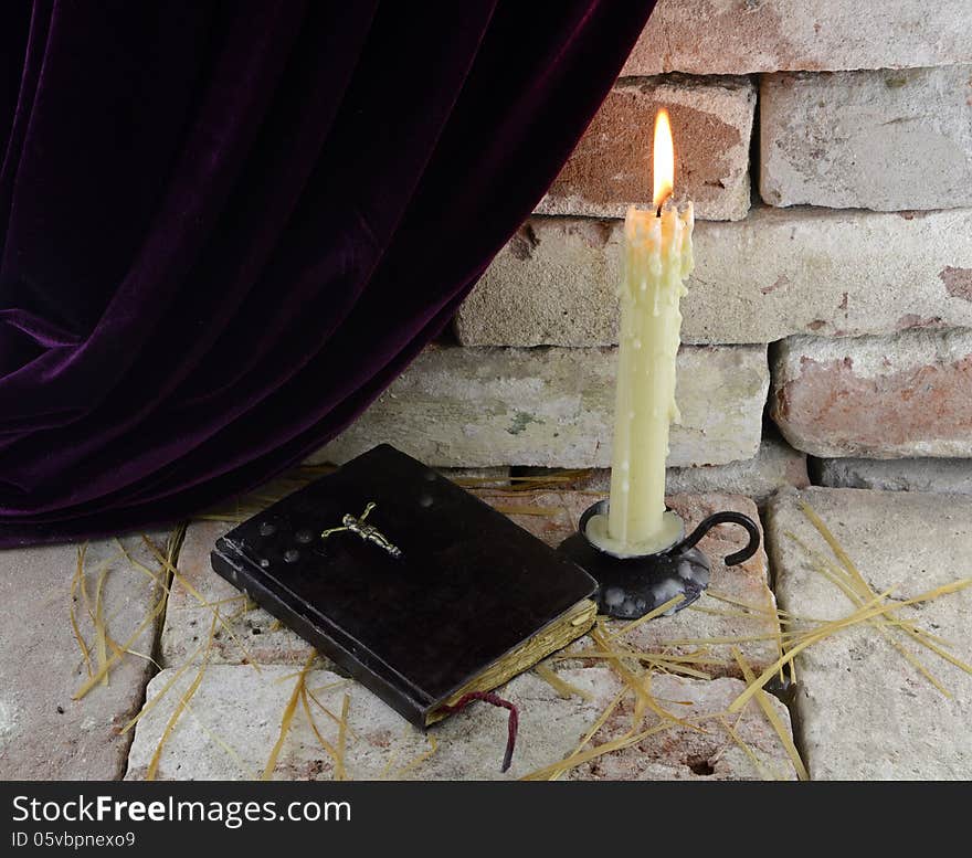 Burning candle with Bible in Gothic castle background