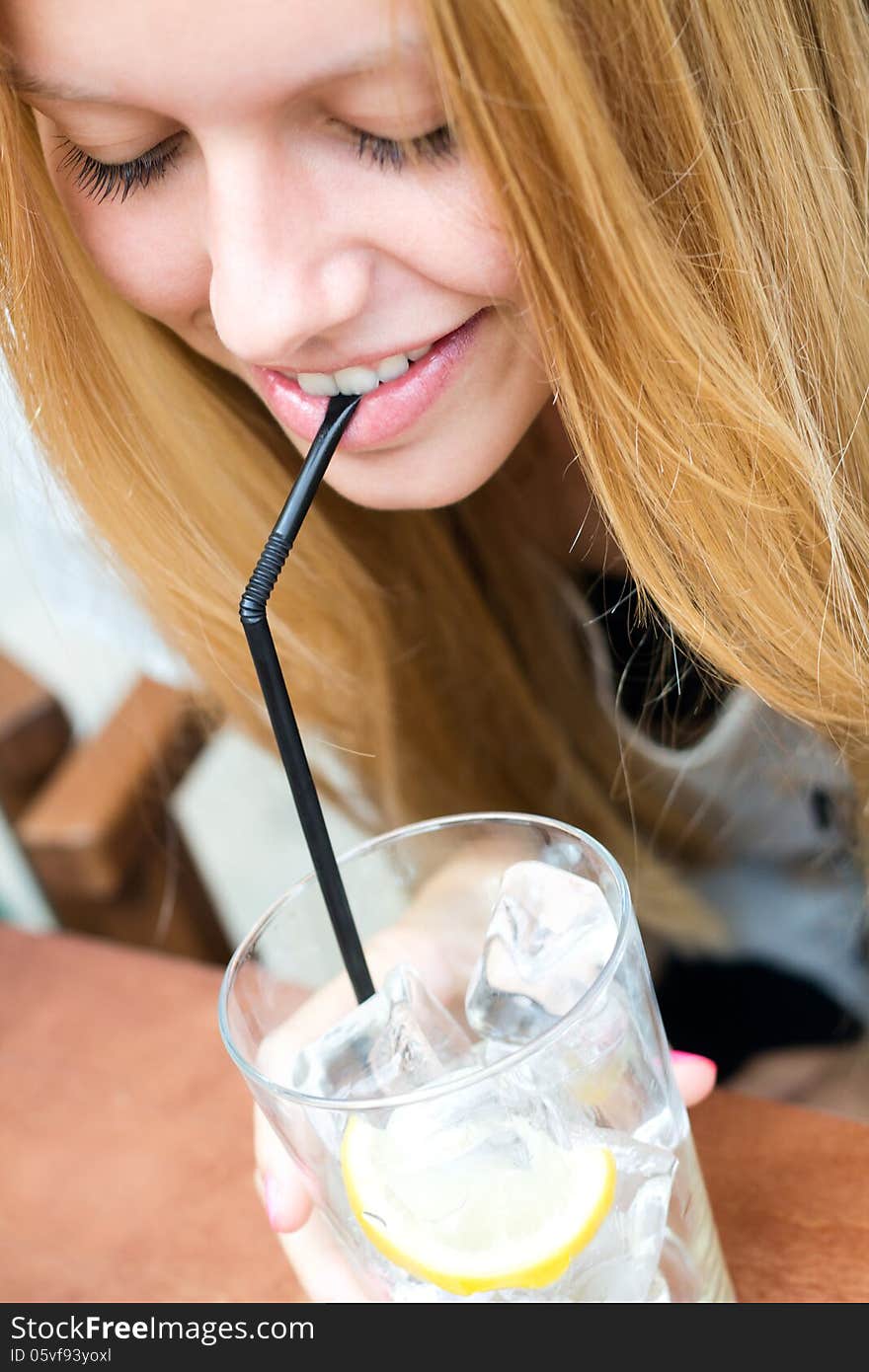 Closeup portrait of Pretty blonde girl taking a drink on a terrace