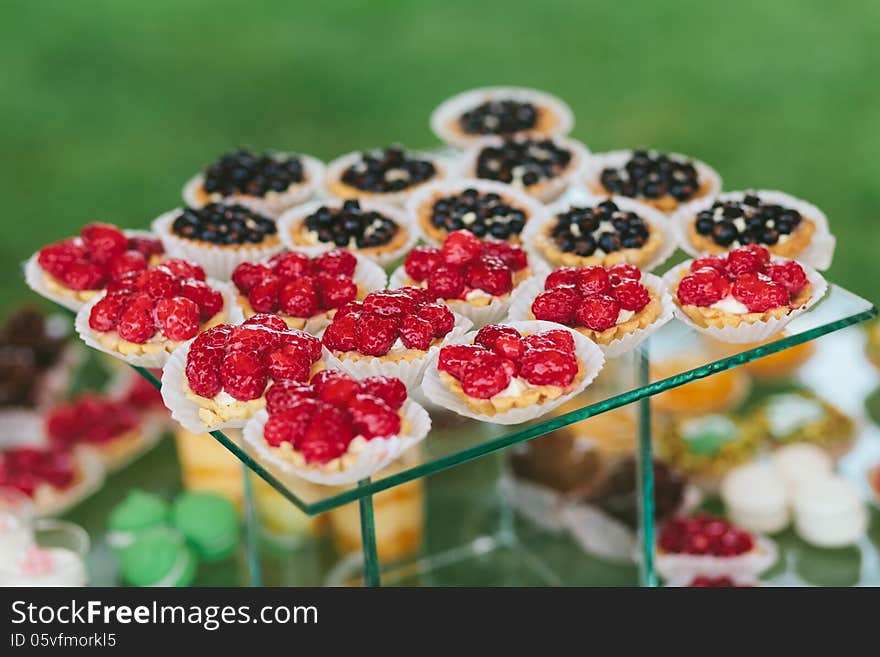 A bunch of fruits cupcakes sitting on glass table with green background. A bunch of fruits cupcakes sitting on glass table with green background.