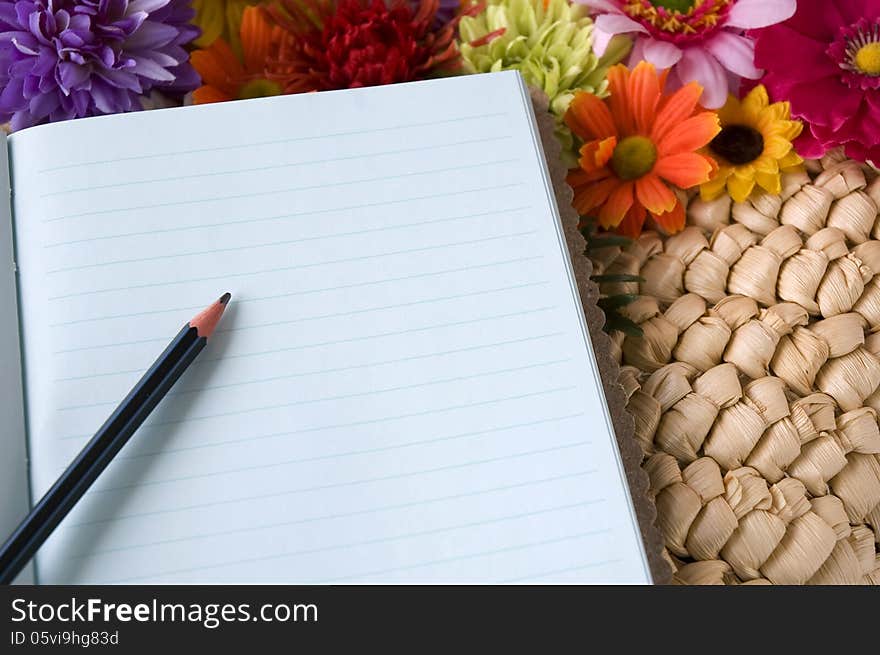 Pencil put on notebook with flowers blooming background