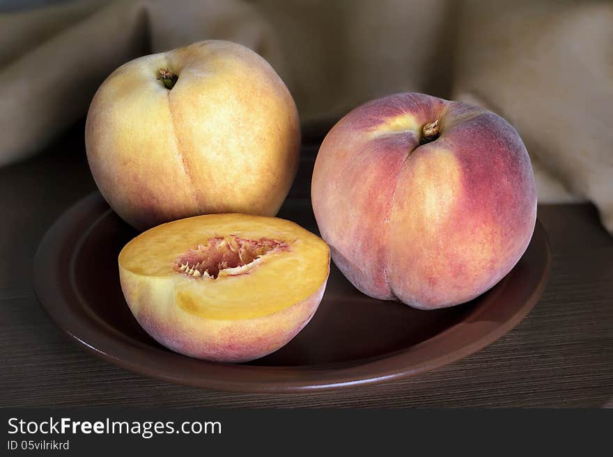 Ripe peaches whole and segments with on a ceramic plate