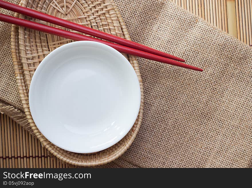 Two chopsticks next to a red and white bowl