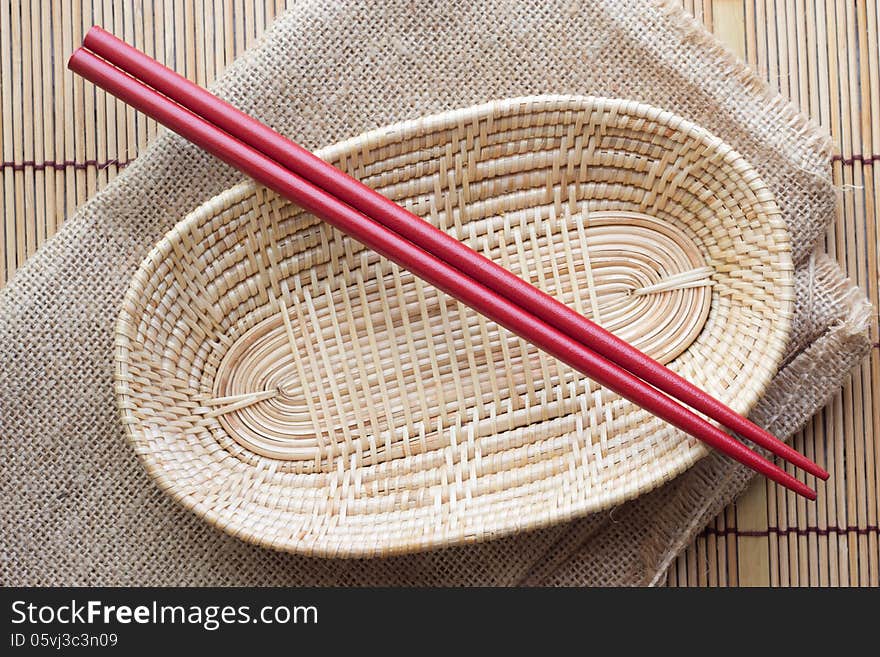 Two chopsticks next to a red and white basket