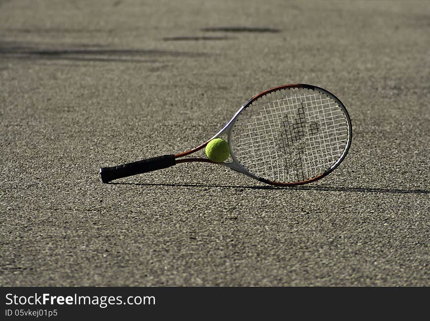 Tennis racket and ball in focus on the ground. Tennis racket and ball in focus on the ground