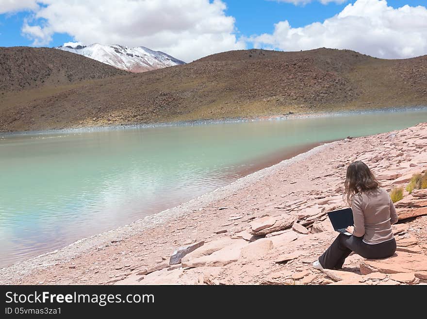 Young girl with laptop on the shore of a mountain lake Laguna Celeste, Bolivia. Young girl with laptop on the shore of a mountain lake Laguna Celeste, Bolivia