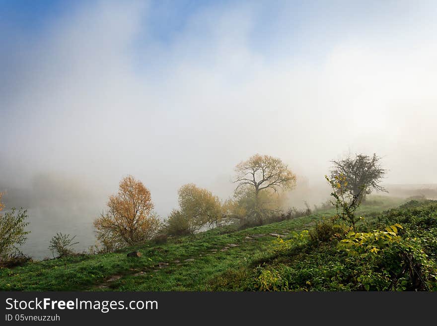 Thick fog on autumn embankment