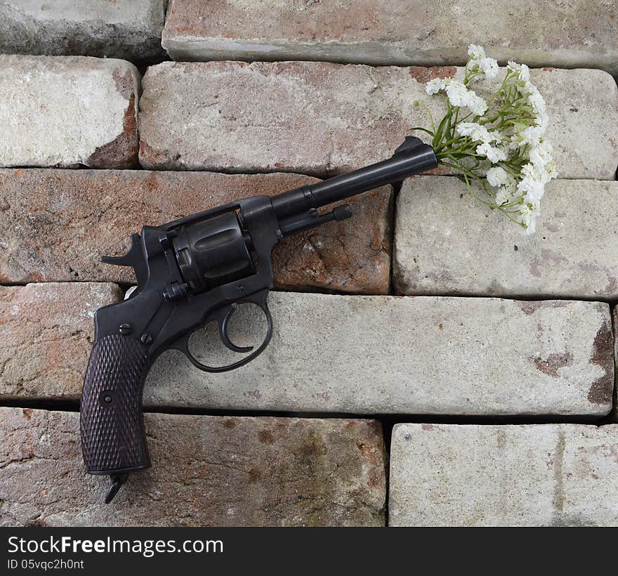 Black retro gun with bunch of flowers on stone background