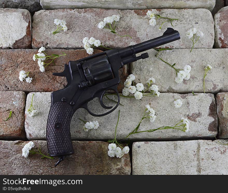 Retro gun with white flowers on brick wall background. Retro gun with white flowers on brick wall background