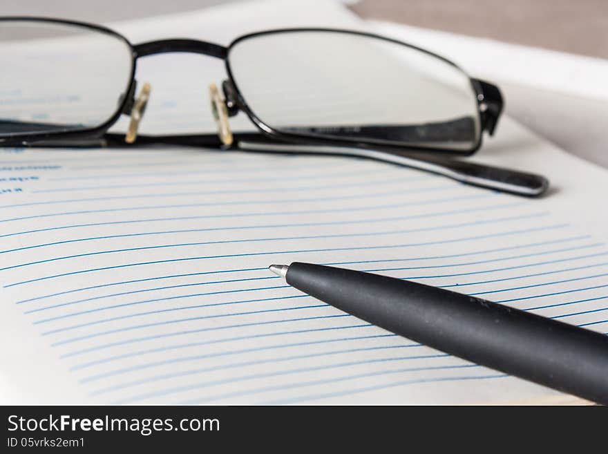 Glasses and pen on a sheet of linear. Glasses and pen on a sheet of linear