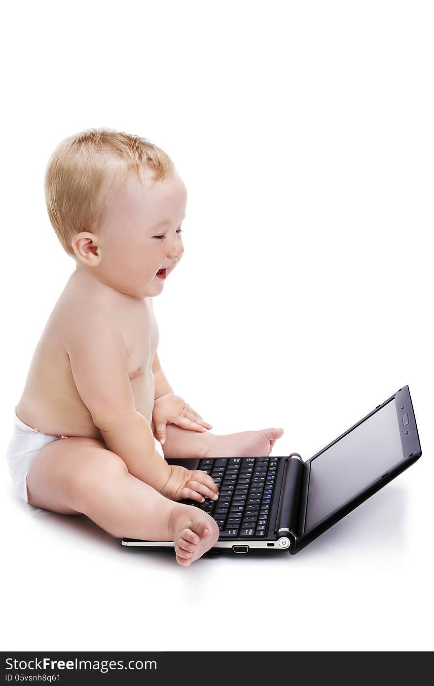 Smiling baby typing on a laptop, positioned sideways, isolated on a white background. Smiling baby typing on a laptop, positioned sideways, isolated on a white background